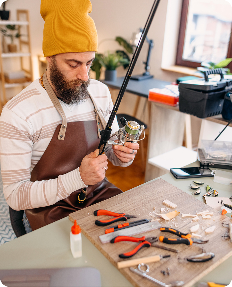 Man repairing fishing rod indoors